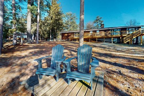 two blue chairs on a deck with a house in the background at Dreams on the Lake in Tomahawk