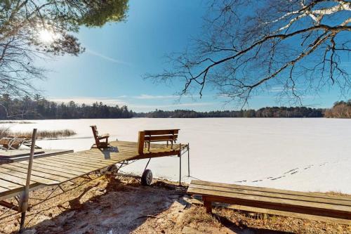 a wooden dock with two benches on a frozen lake at Dreams on the Lake in Tomahawk