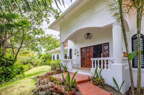 a white house with a red door and trees at Private Pool Villa - BBQ - Washer in Sosúa