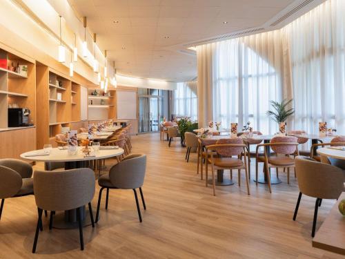 a dining room with tables and chairs and windows at Mercure Tours Nord in Tours