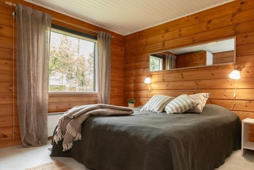 a bedroom with a bed with wooden walls and a window at Rukan Talvihovi in Ruka