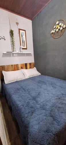 a bedroom with a bed with a blue blanket at Chácara Maira e Araken in Ibiúna