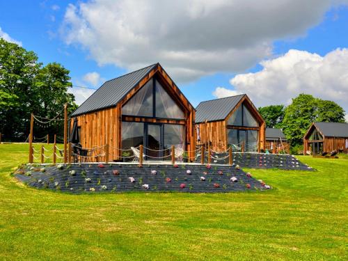 a wooden house with a playground in a field at Mazurskie Stodoły in Piecki