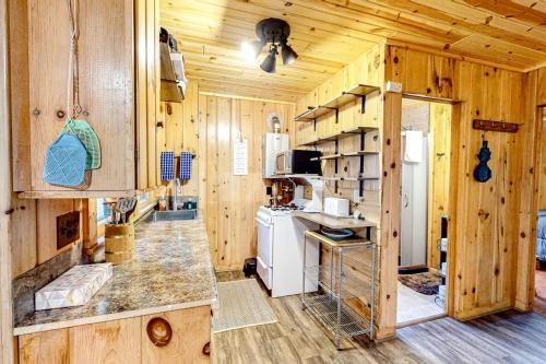 a kitchen with wooden walls and wooden flooring in a cabin at Dragonfly Gully in Rhinelander