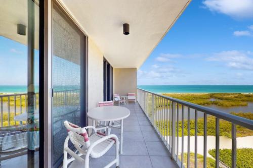 a balcony with a table and chairs and the ocean at The Breezy Perch in Marco Island