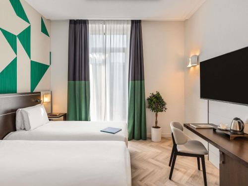 a hotel room with two beds and a desk at Mercure Napoli Centro Angioino in Naples