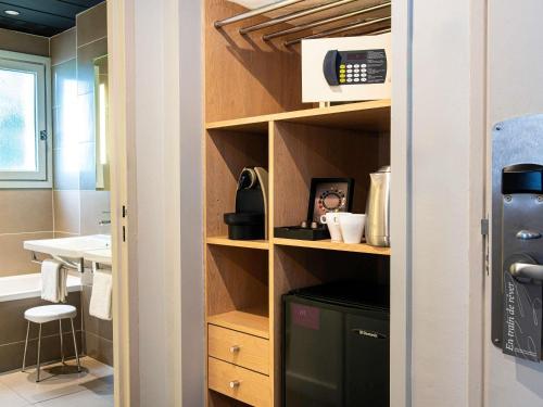 a kitchen with a sink and a shelf with a microwave at Mercure Carcassonne La Cité in Carcassonne