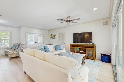 a living room with white furniture and a flat screen tv at The Sunshine Social in Naples