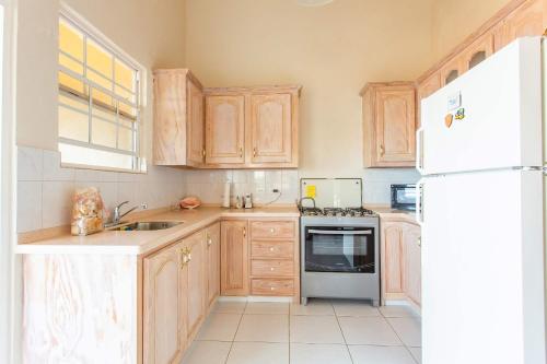 a kitchen with wooden cabinets and a white refrigerator at Oceanview Terrace, Walk to Beach, WiFi and Parking in Saint Lucy