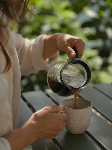 a woman pouring coffee into a cup on a table at Cabaña el Refugio Buenavista in Buenavista