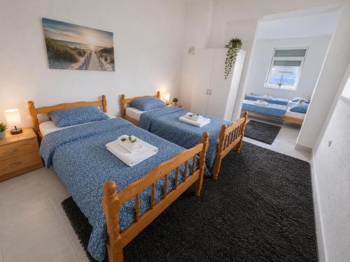 a bedroom with two beds with blue sheets at Apartmani Velić in Bugojno