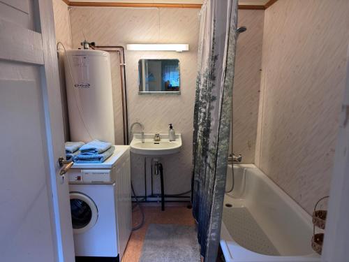 a small bathroom with a sink and a tub and a washing machine at Hundevennlig feriehus ved sjøen på Geisnes in Sørmoen
