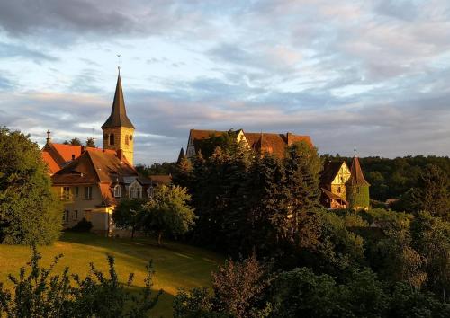 a house with a church in the middle of a field at Appartment Schlossblick in Wiesenthau