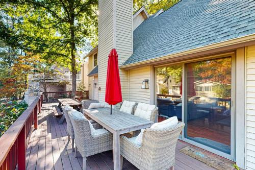 a patio with a table with a red umbrella and chairs at Battersea on the Canal in Ocean Pines