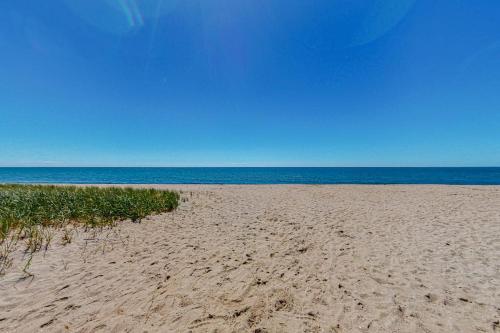a sandy beach with the ocean in the background at Maushop By The Sea in Mashpee