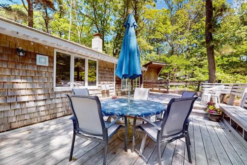 a table with chairs and an umbrella on a deck at The Woodland Cottage in Eastham