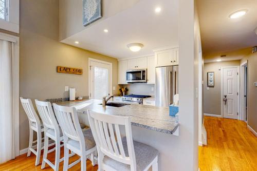 a kitchen with a bar with white chairs in it at Seabury Serenity in New Seabury