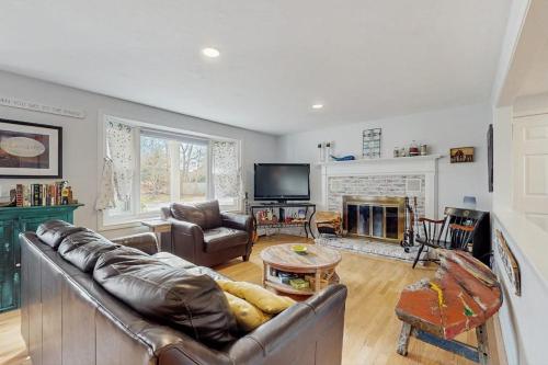 a living room with a leather couch and a fireplace at The Blue Whale Cottage in Brewster