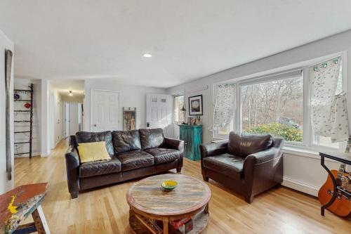 a living room with two leather couches and a table at The Blue Whale Cottage in Brewster