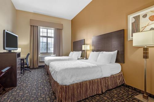a hotel room with two beds and a flat screen tv at Best Western Plover-Stevens Point Hotel & Conference Center in Plover