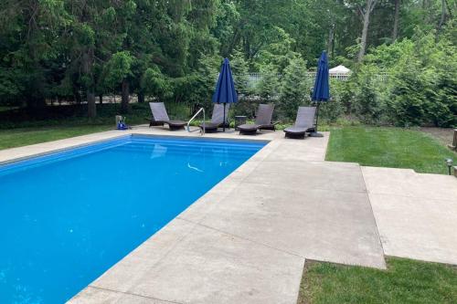 a swimming pool with chairs and blue umbrellas at Ravenswood Pool House in Sawyer