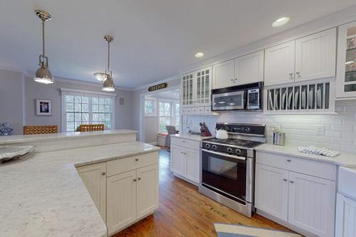 a large kitchen with white cabinets and a stove top oven at Cotuit Mannor in Cotuit