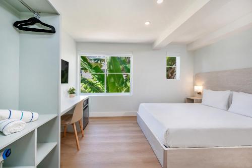 a white bedroom with a bed and a desk at Casa Collins in Miami Beach