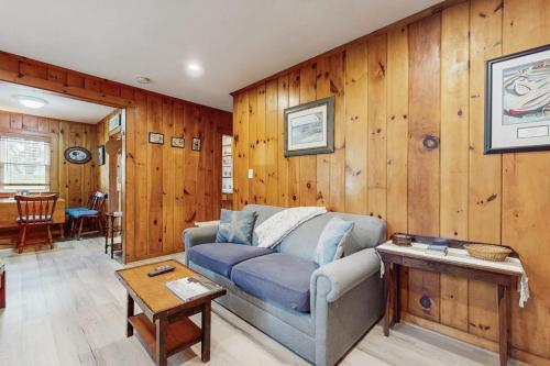 a living room with a blue couch and wooden walls at Uncle Rolfs Cozy Cottage in Dennis Port