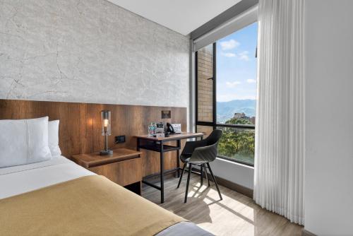 a hotel room with a bed and a desk and a window at Cafe Hotel Medellín in Medellín