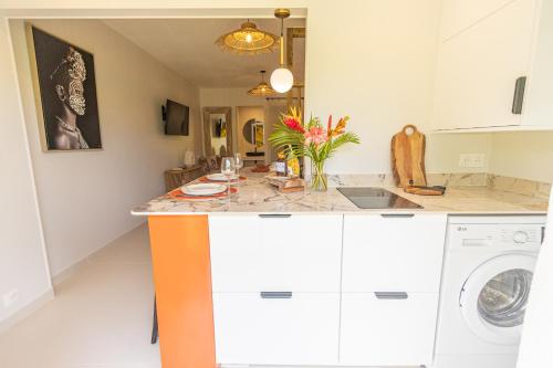a kitchen with an orange island with a washing machine at Studio Le Cosy Jungle & Piscine in Pointe-à-Pitre
