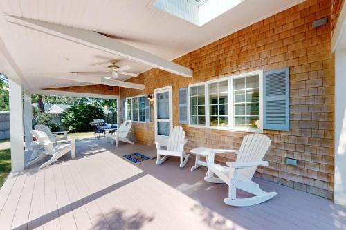 a patio with white chairs and a table at Seaside Park Retreat in West Hyannisport