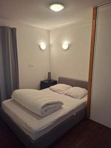a bedroom with a bed with white sheets and two pillows at Le Nid du Sancy - Les Matins du Sancy - Super-Besse in Super Besse