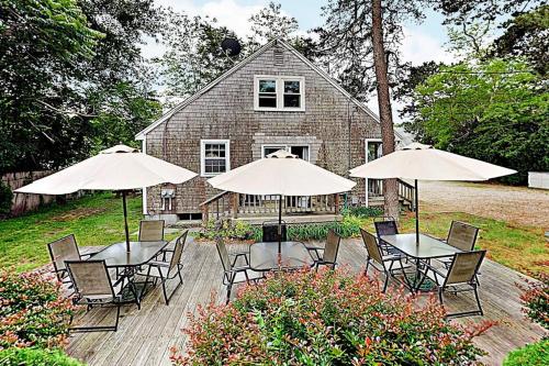 a group of tables with umbrellas in front of a house at Dennis Port Palace in Dennis Port