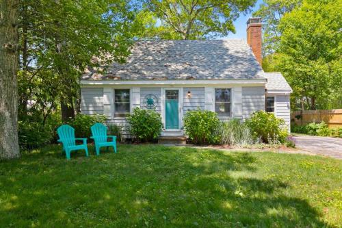 a white house with two blue chairs in the yard at Dolce Vita in Falmouth
