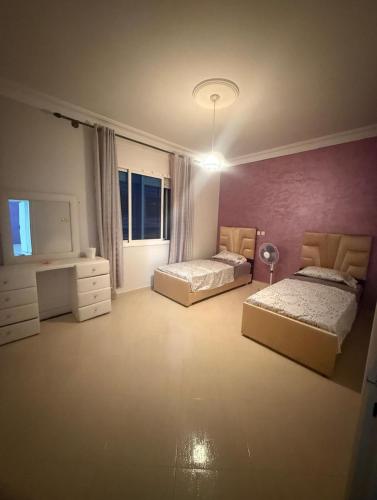 a bedroom with two beds and a desk and a window at Villa Familiale Exception in Saïdia