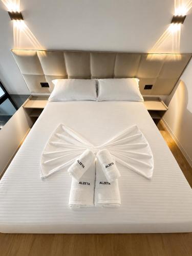 a bed with two white towels on top of it at ALZETA Aparthotel in Durrës