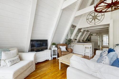 a living room with white furniture and a kitchen at Mt McSauba A Frame Cottage in Charlevoix