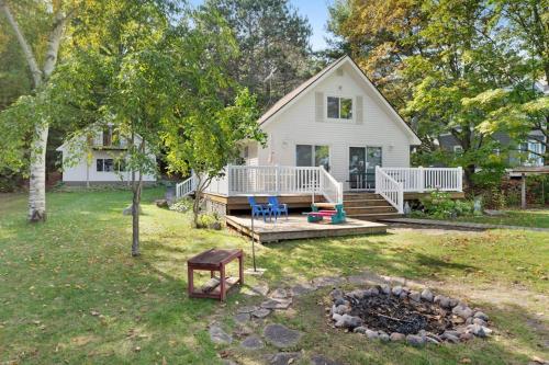 a white house with a porch and a fire pit at Walloon Lake Cottage in Boyne City