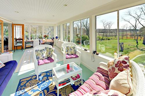 a living room with a couch and chairs and windows at Brookview Bungalow in South Wellfleet