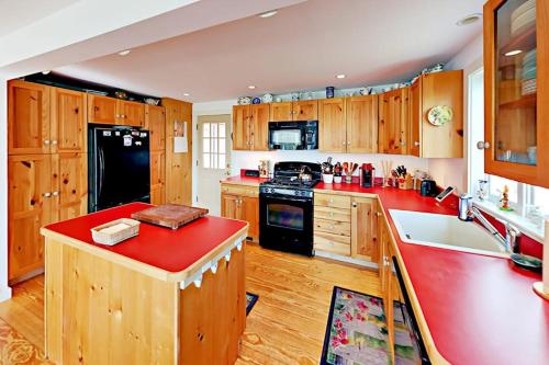 a kitchen with wooden cabinets and a red counter top at Brookview Bungalow in South Wellfleet