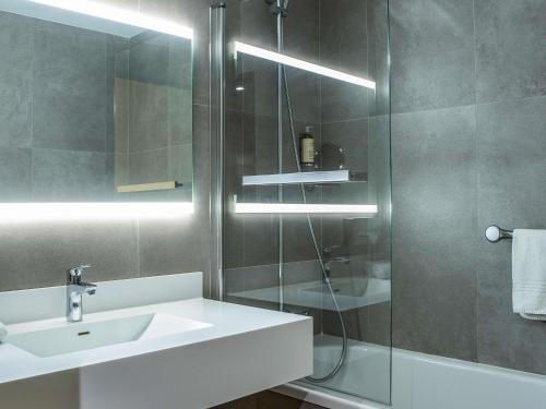 ein Badezimmer mit Waschbecken und Glasdusche in der Unterkunft Mercure Vannes Le Port in Vannes