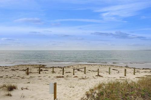 a beach with a fence in the sand and the ocean at Seashore Escape in North Truro