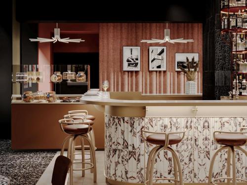 a kitchen with a counter and a bar with stools at TRIBE Strasbourg Centre Gare in Strasbourg