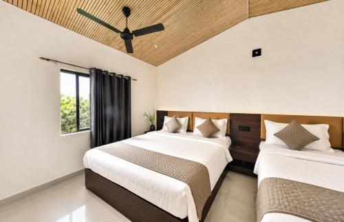 two beds in a bedroom with a ceiling fan at Gir Wildtrack Lodge - Into the Deep Forest in Sasan Gir