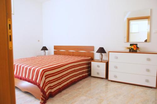 een slaapkamer met een bed, een dressoir en een spiegel bij Appartamento Roberti in Corsano
