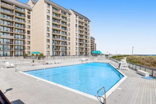 a swimming pool with chairs and a building at Sea Colony --- 1BB Brandywine Garden in Bethany Beach