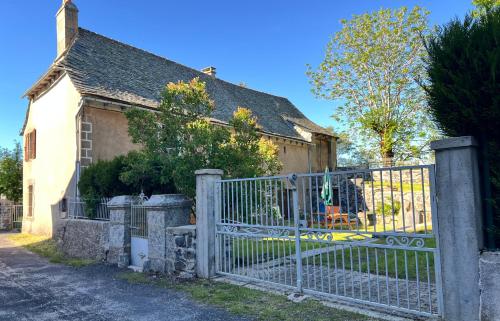 a fence in front of a house with a yard at Le Refuge de l'Argence in Alpuech