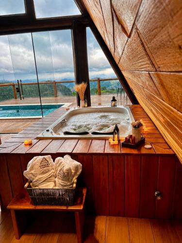 a bath tub in a room with a large window at Chalés La Montagna in Santa Teresa