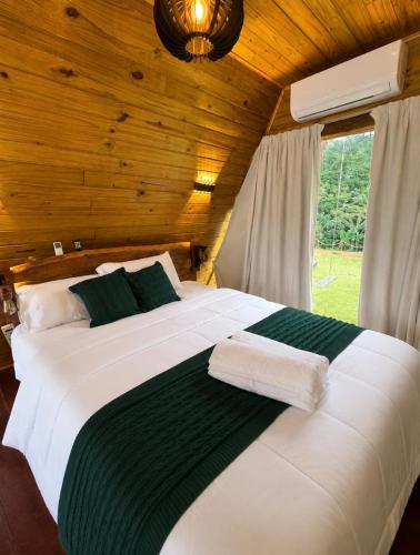 a bedroom with a large white bed with a wooden ceiling at Chalés La Montagna in Santa Teresa