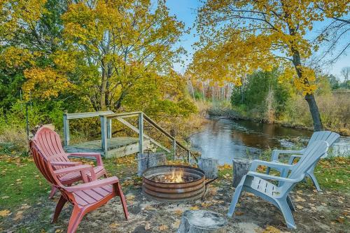 drei Stühle und eine Feuerstelle neben einem Fluss in der Unterkunft Riverside Abode in Thompsonville